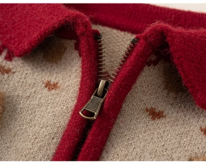 Detail of red knitted neckline and bronze zipper on beige children sweater cardigan