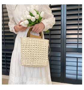 Detailed close-up of straw woven bag with vintage dark brown wooden round handles