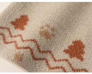 Detail of knitted fabric showing tree and cat paw patterns on soft grey wool material