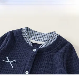 Detailed view of dark blue knit cardigan with V-neck patchwork and light blue bow