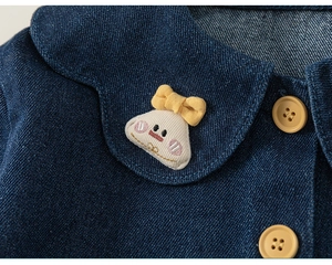 Detail eines blauen Jeanshemds für Mädchen mit Peter Pan Kragen und Plüschfigur