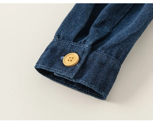 Detaillierte Makroansicht einer dunkelblauen Jeansmanschette mit gelbem Harzknopf