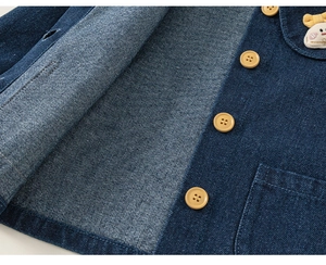 Detailansicht des Denimstoffs mit süßer Hasenstickerei und gelben Knöpfen am Hemd