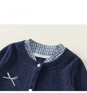 Detail view of navy ribbed knit cardigan collar with bow and blue plaid shirt pattern