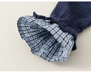 Detail of dark blue ribbed knit sleeve with blue and white plaid ruffle trim