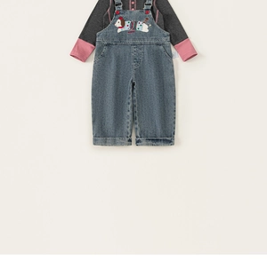Detail showing the cartoon dog embroidery on denim overalls for little girls