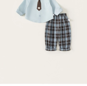 Detailed flat lay of boys blue dress shirt with bear tie and brown plaid trousers
