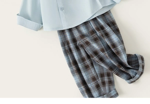 Close-up of boys light blue short sleeve shirt with classic checkered pants detail