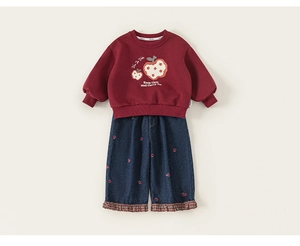 Detailweergave van rood sweatshirt met appelprint en jeansset met hartborduring