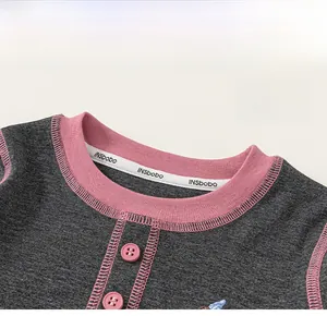 Detail of pink contrast neckline and buttons on gray long sleeve children t-shirt