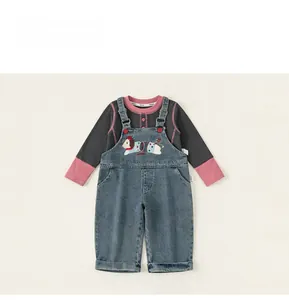 Detailed view of kids denim overalls with dog embroidery and a contrast long sleeve t-shirt