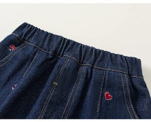 Detail van donkerblauwe kinderjeans met rode hartborduring en elastische taille