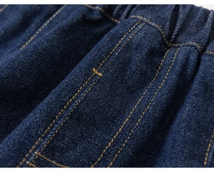 Detail van de elastische tailleband met oranje stiksels op donkerblauwe denim stof