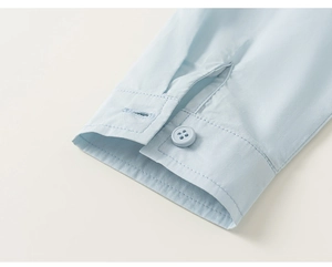 Close-up detail of light blue cotton shirt cuff with premium stitching and button