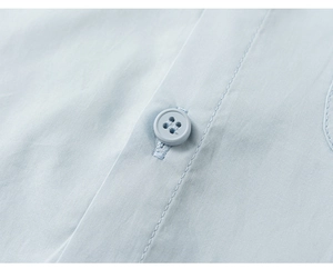 Close-up of fine stitching and matching button on a blue cotton children's dress shirt