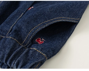 Detail van de elastische tailleband op donkerblauwe denim met rode hartborduring