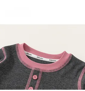 Detail of grey knitted kids top featuring pink ribbed neckline and cute button closure