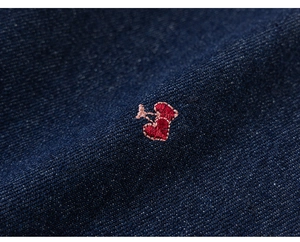 Detail van rood hart borduursel op premium donkerblauw denim met een twill textuur