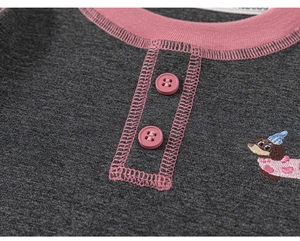 Macro detail of toddler knit shirt featuring pink trim, buttons, and puppy embroidery