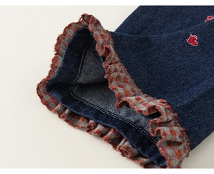 Detail van denim broek met geruite ruches en rode hartborduring voor meisjes