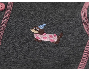Close-up of dachshund embroidery and pink button on grey knitted cotton children clothing