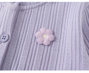 Close-up of purple knitted fabric with flower embroidery and matching round button
