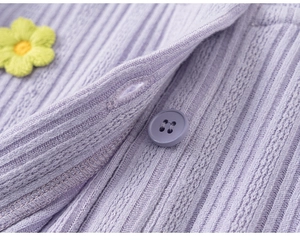 Detailed close-up of light purple ribbed knit cardigan with yellow floral embroidery