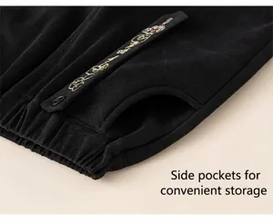 Detail of black knit trousers featuring elastic waist and gold pattern decorative side tape