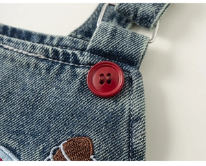 Detailed macro shot of blue denim fabric with vibrant red button and white contrast stitching