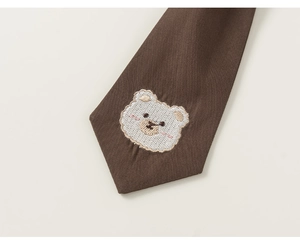 Detailed close-up of dark brown necktie featuring a cute white bear embroidery detail