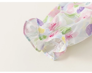 Detailed view of elastic ruffled cuffs with vibrant watercolor floral print on cotton fabric