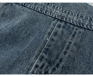 Detail of dark blue denim fabric showing double stitching and washed texture