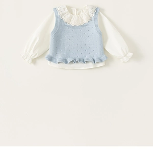 Detail of girls knit vest and white shirt featuring hollowed lace ruffle collar