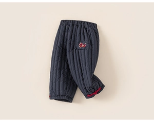 Detail van de donkerblauwe gewatteerde winterbroek met borduursel en rode strikjes