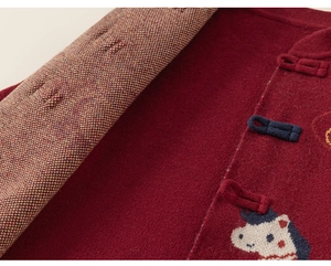 Detail van rood gebreid vest met traditionele knopen en borduursel voor kinderen