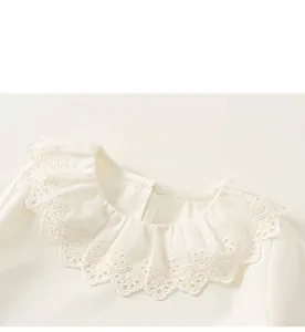Detail view of the delicate eyelet lace collar and ruffled edges on the cotton blouse