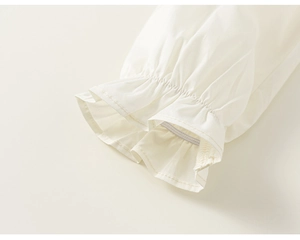 Close-up detail of elastic ruffled cuffs on a girls white cotton blouse set