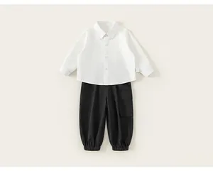 Flat lay of boys white long-sleeved shirt and black cargo pants set with cuffed ankles
