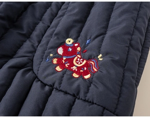 Detail van donkerblauwe gewatteerde stof met een kleurrijke geborduurde pony op een kinderjas