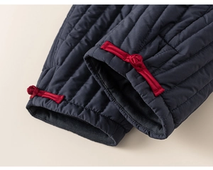 Detail van donkerblauwe gewatteerde stof met traditionele rode Chinese knoopsluiting