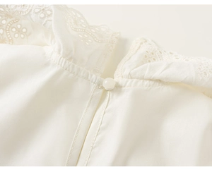 Detail of white cotton shirt neckline with delicate hollow lace embroidery and button