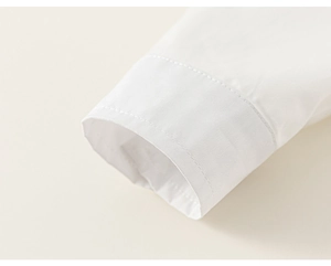 Detailed close-up of white cotton shirt cuff with neat stitching on beige background