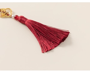 Détail d'un gland rouge traditionnel avec breloque nuage dorée et perles pour Qipao