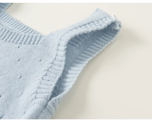 Detail of light blue knitted vest featuring small hollow dot patterns and size 90 label