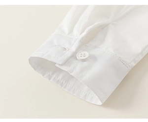 Close-up detail of white cotton shirt sleeve cuff with white resin button and neat stitching