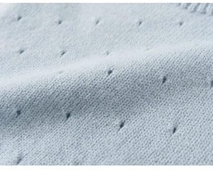 Detailed macro view of light blue knitted fabric with breathable eyelet hole patterns