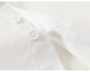 Detailed close-up of white cotton shirt fabric texture and fine stitching on the cuff
