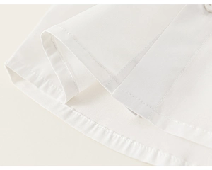 Detailed close-up of white cotton shirt hem with precise stitching and round button