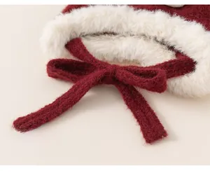Détail du bonnet en tricot rouge avec bordure en peluche blanche et lacets