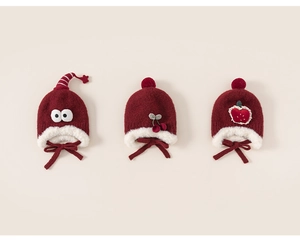 Détail de bonnets en tricot rouge pour bébé avec décors de cerise et de fraise